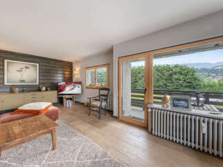 Experience breathtaking mountain views from this charming living room, featuring a cozy seating area and a large sliding glass door that opens to a private balcony.