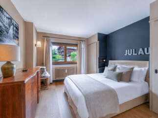 Experience comfort and style in this beautifully appointed bedroom, featuring a plush king-sized bed adorned with decorative pillows and a cozy throw.