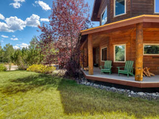 Experience rustic charm with this beautiful log home, featuring a spacious covered porch perfect for enjoying the serene natural surroundings.