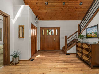 Step into this inviting entryway featuring warm hardwood floors and a stunning wood-paneled ceiling.
