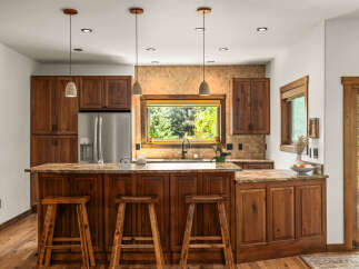 Experience rustic charm in this beautifully appointed kitchen, featuring rich wooden cabinetry and a stunning granite-topped island perfect for casual dining.