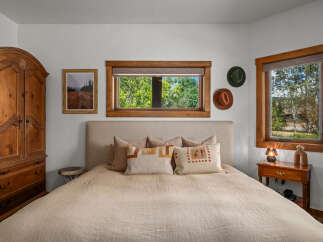 Experience rustic charm in this inviting bedroom, featuring a cozy queen-size bed adorned with decorative pillows and a textured headboard.