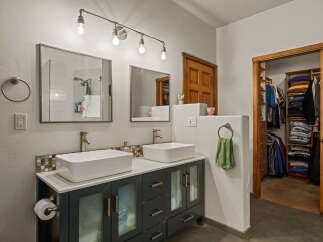 This modern bathroom features a dual vanity with vessel sinks and sleek dark cabinetry, complemented by a stylish track lighting fixture.