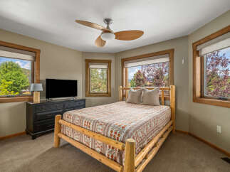 Experience rustic charm in this cozy bedroom, featuring a beautiful log-frame bed adorned with a vibrant, patterned quilt.
