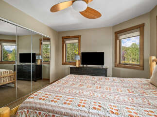 This charming bedroom offers a serene retreat with its large mirrored closet doors reflecting the beautiful mountain views outside.