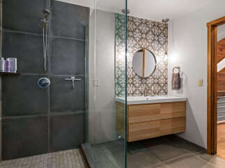 Experience modern luxury in this stunning bathroom featuring a spacious walk-in shower with sleek dark tile and a convenient handheld showerhead.