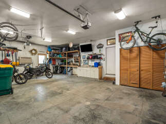 This spacious garage offers ample storage solutions, including overhead bike racks and wall-mounted tool organizers, perfect for hobbyists and car enthusiasts alike.