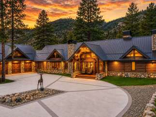 Experience luxury mountain living in this stunning log and stone estate, nestled against a backdrop of majestic peaks and vibrant sunset skies.