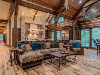 Experience rustic luxury in this stunning lodge-style living room, featuring a grand stone fireplace and exposed wooden beams.