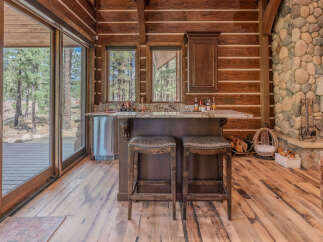 Experience rustic charm in this log cabin featuring a well-appointed bar area with granite countertops and comfortable seating.