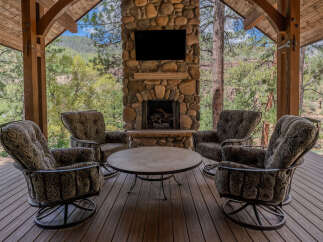 Experience ultimate relaxation on this covered porch, featuring a cozy seating area with plush armchairs arranged around a central coffee table.