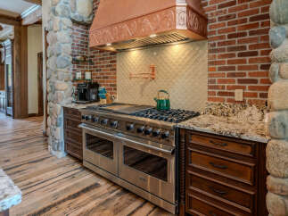 Experience luxury in this stunning kitchen, featuring a professional-grade stainless steel range and a striking copper range hood.