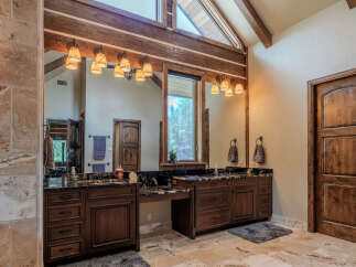 Experience luxury in this spacious master bathroom, featuring dual vanities with granite countertops and rich wood cabinetry.
