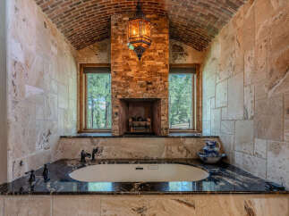 Indulge in luxury with this stunning bathroom featuring a deep soaking tub set against a backdrop of natural stone and brick.