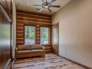 Experience rustic charm in this inviting room featuring a cozy leather sofa positioned before large windows that offer scenic views.