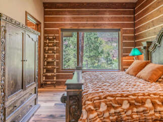 Experience rustic luxury in this charming bedroom, featuring a stunning log-style wall and a large window with breathtaking mountain views.