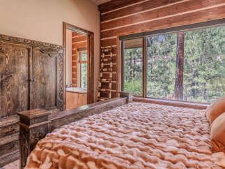Experience rustic luxury in this charming bedroom featuring a beautifully carved wooden wardrobe and a cozy bed adorned with a plush faux fur blanket.