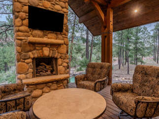 Experience ultimate relaxation on this covered patio, featuring a grand stone fireplace and comfortable seating.