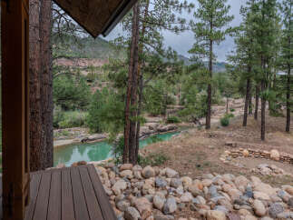 Experience serene living with this stunning property featuring a private turquoise riverfront and lush pine forest surroundings.
