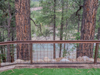 Experience breathtaking views of a serene river from this property, framed by majestic pine trees.