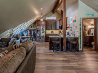 Discover this charming attic apartment featuring a cozy living area with a plush sofa, a well-equipped kitchen with dark wood cabinetry and granite countertops, and a convenient dining space.