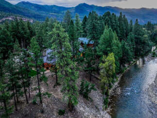 Experience serene mountain living in this stunning log cabin nestled amongst towering pine trees and adjacent to a flowing river.