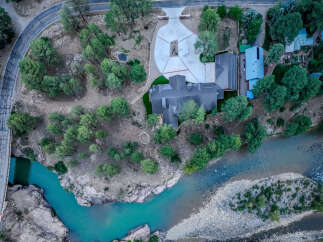 Experience luxury living with this stunning aerial view of a modern estate nestled beside a vibrant turquoise river.