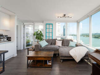 Experience breathtaking waterfront views from this stunning condo, featuring a spacious sectional sofa perfect for relaxing.