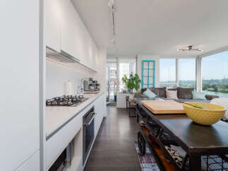 Experience modern living in this stunning open-concept condo, featuring a sleek white kitchen with integrated appliances and a spacious island perfect for entertaining.