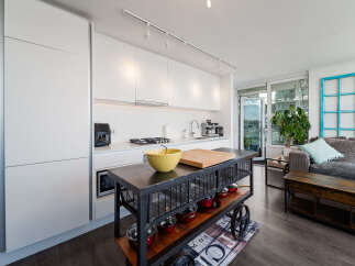 Discover modern urban living in this stylish condo featuring a sleek white kitchen with integrated appliances and a functional island.
