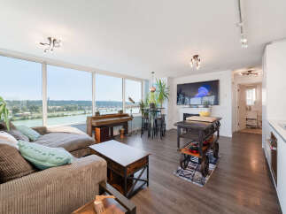 Experience breathtaking waterfront views from this stunning condo, featuring a spacious living area with a cozy sectional sofa and a unique piano.