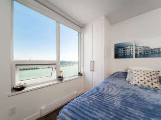 Experience breathtaking waterfront views from this stunning bedroom, featuring expansive windows that flood the space with natural light.
