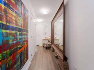 This hallway features a vibrant abstract painting on the left wall, adding a pop of color to the space.