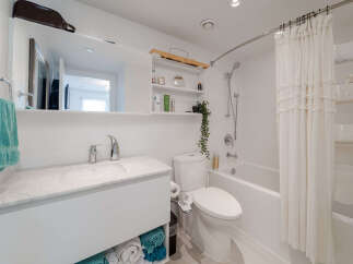 This modern bathroom features a sleek vanity with a marble countertop and ample storage, complemented by a stylish chrome faucet.