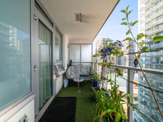 Enjoy urban living with this charming balcony, featuring artificial turf flooring and a cozy seating area perfect for relaxation.