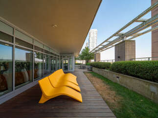 Enjoy breathtaking city views from this expansive rooftop terrace, featuring modern yellow lounge chairs perfect for relaxation.