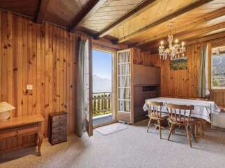 Experience breathtaking mountain views from this charming dining area, featuring a rustic wooden interior and a crystal chandelier.