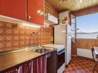 Charming retro kitchen featuring vibrant orange cabinetry and a classic tiled backsplash.