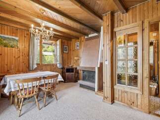 Step into a charming rustic retreat featuring a cozy dining area with a traditional chandelier and a picturesque landscape painting.
