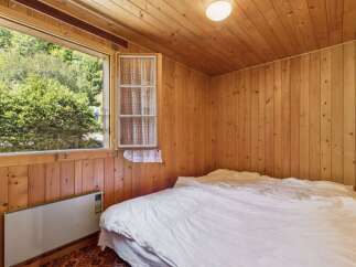 Experience rustic charm in this cozy bedroom, featuring warm wood-paneled walls and a ceiling that exudes natural beauty.