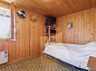 This cozy bedroom features charming wood-paneled walls and ceiling, creating a warm and inviting atmosphere.