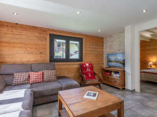 Experience cozy living in this charming mountain retreat, featuring warm wood paneling throughout and a comfortable sectional sofa perfect for relaxation.
