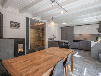 Experience modern living in this open-concept dining and kitchen area, featuring a cozy fireplace and a sleek, contemporary kitchen.