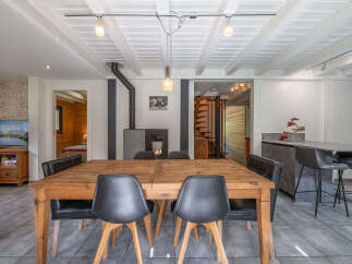 This spacious dining area features a rustic wooden table with comfortable black chairs, perfect for family gatherings.