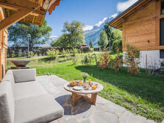 Enjoy a delightful breakfast on this charming patio, complete with a comfortable outdoor sofa and a rustic wooden table set for two.
