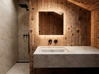 Experience rustic luxury in this modern bathroom featuring warm, natural wood paneling and a sleek, integrated stone sink.