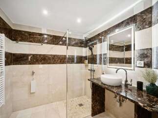 Experience modern luxury in this stunning bathroom, featuring a spacious walk-in shower with elegant marble tilework.