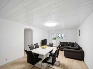 This spacious living and dining area features a modern white dining table with six black chairs, perfect for family meals.