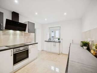 Discover this modern kitchen featuring sleek cabinetry and a stylish black range hood.