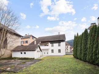 Discover this charming property featuring a spacious white house with multiple windows and a dark-tiled roof, complemented by a separate white outbuilding.